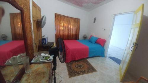 1 dormitorio con cama, espejo y ventana en Fay Guest House en Negril