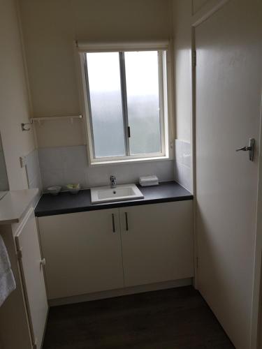 baño pequeño con lavabo y ventana en Phillip Island Cottages, en Cowes