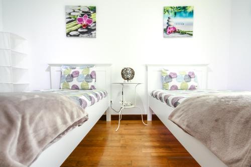 two beds in a room with white walls and wooden floors at Apartamento Tejo in Cacilhas