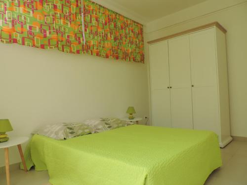 Un dormitorio con una cama verde y una pintura en la pared en Any's Appart, en Fort-de-France