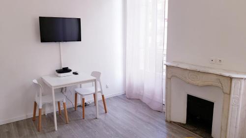 - un salon avec une table et une télévision près de la cheminée dans l'établissement Cosy central studio Nice Rossini large balcony, à Nice