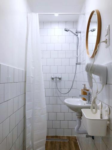 a white bathroom with a sink and a mirror at Chesscom Guesthouse in Budapest