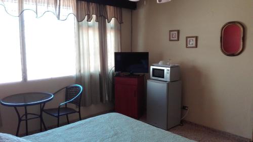 a bedroom with a bed and a television and a table and chairs at Casa San Benito in San Salvador
