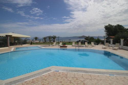 a large blue swimming pool with chairs and umbrellas at UMBRELLA BEACH APARTMENTs in Kavos