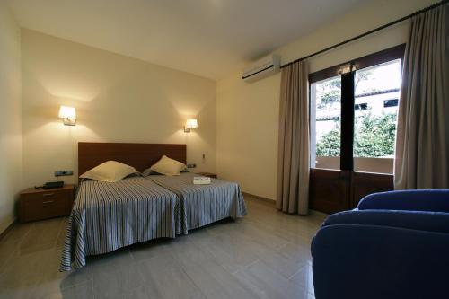 Habitación de hotel con cama y ventana en Hotel Sa Riera, en Begur
