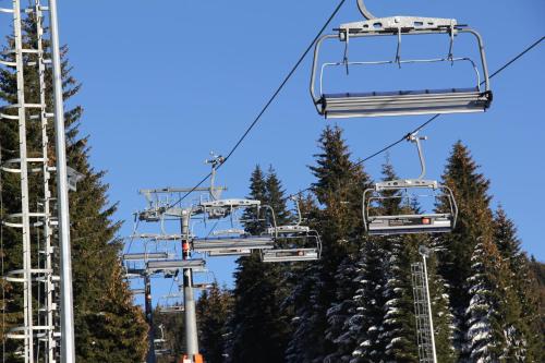 a ski lift going up a mountain with trees at Kopaonik011 Konaci&WoodSide Apartments in Kopaonik