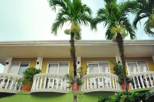 a yellow house with palm trees in front of it at Hotel Malinche in Quepos