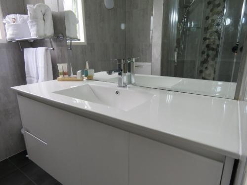 a white bathroom with a sink and a shower at Grandeur Thermal Spa Resort in Taupo