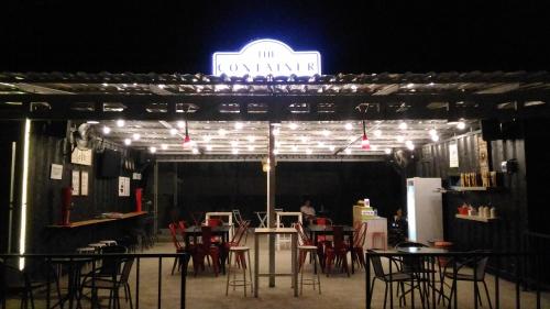 un restaurant avec des tables et des chaises et un panneau de néon dans l'établissement The Container, à Labuan Bajo