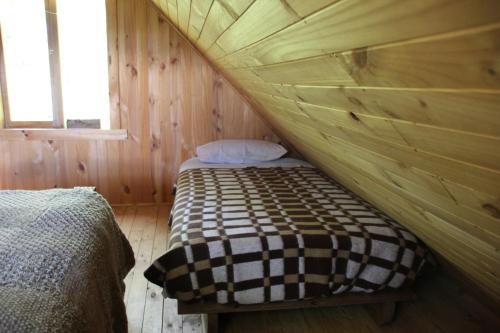 1 dormitorio con 1 cama en una habitación de madera en Conguillio Cabaña Chercan, en Conguillio