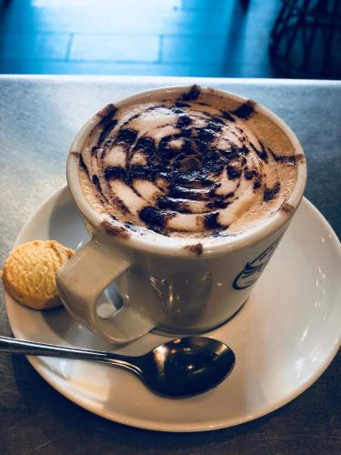 a cup of coffee on a plate with a biscuit at The Belmore in Sale