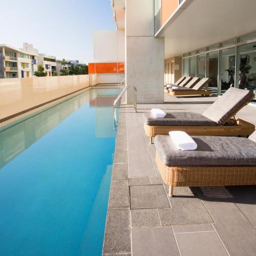 a swimming pool with two chaise lounges next to a building at Mantra South Bank Brisbane in Brisbane