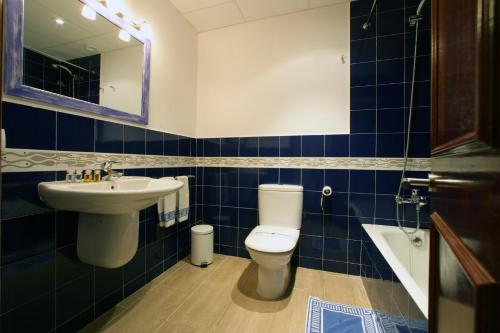 a blue tiled bathroom with a toilet and a sink at Hotel Sa Riera in Begur