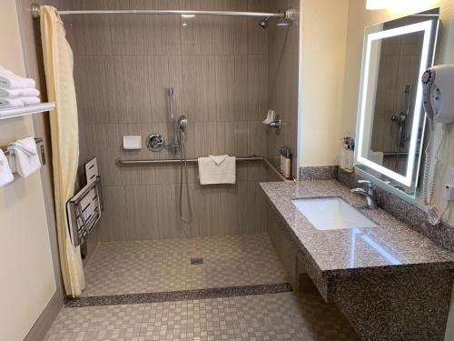 a bathroom with a shower with a sink and a mirror at El Castell Motel in Monterey