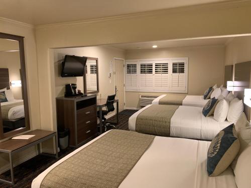una camera d'albergo con due letti e una televisione di El Castell Motel a Monterey