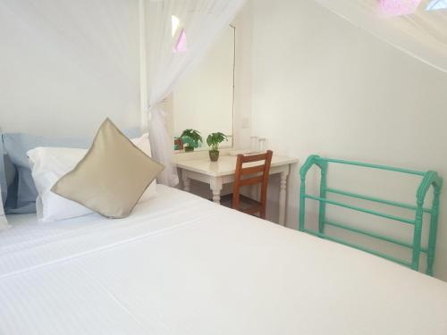 a bedroom with a white bed and a table at Neela's Beach Inn in Hikkaduwa