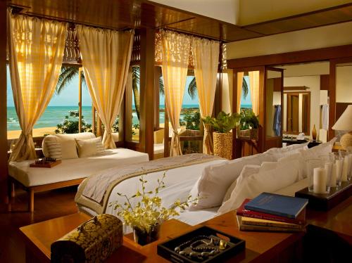 Tanjong Jara Resort - Small Luxury Hotels of the World في دونجون: غرفة نوم مع سرير وإطلالة على المحيط