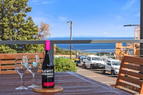 una botella de vino sentada en una mesa con dos copas en Seahaven - Sellicks Beach - C21 SouthCoast Holidays en Sellicks Beach