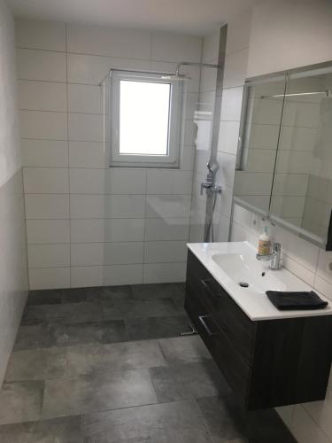 baño con lavabo, espejo y ventana en Sunnesching, en Schuld