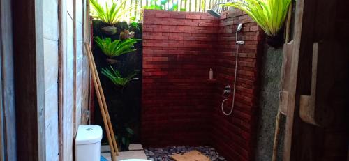 a bathroom with a red brick shower with plants at Umaya Ubud Villa in Ubud