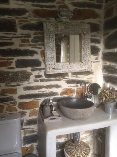 a bathroom with a sink and a mirror on a stone wall at The Hill Top House in Kea in Ioulis