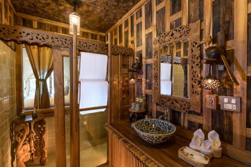 ein Badezimmer mit Holzwänden, einem Waschbecken und einem Spiegel in der Unterkunft Santhiya Tree Koh Chang Resort in Ko Chang