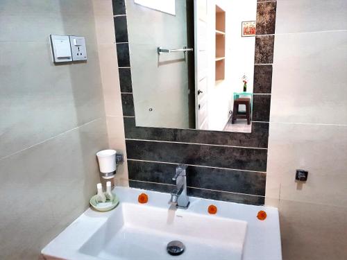 een badkamer met een witte wastafel en een spiegel bij Neela's Beach Inn in Hikkaduwa