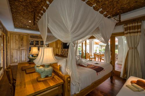 a bedroom with a canopy bed and a table with a lamp at Santhiya Tree Koh Chang Resort in Ko Chang