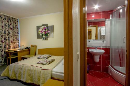 a room with a bed and a bathroom with a sink at Tourist Hotel in Minsk