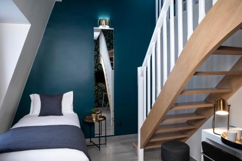 a bedroom with blue walls and a bed and a staircase at Hôtel Brady in Paris