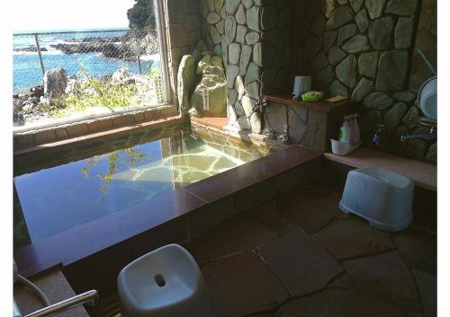 a bathroom with a tub and a toilet and a window at 海のお宿 in Susami