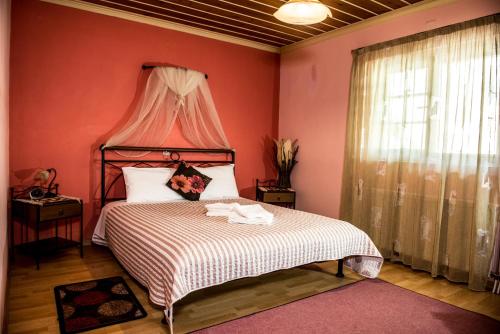a bedroom with a bed with a red wall at Guesthouse To Tzaki, in Konitsa