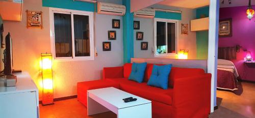 sala de estar con sofá rojo y almohadas azules en El Desván Escondido, en Conil de la Frontera