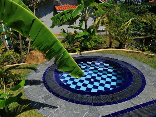 a blue pool with a checkered floor in a garden at Thambili Cabanas in Hikkaduwa