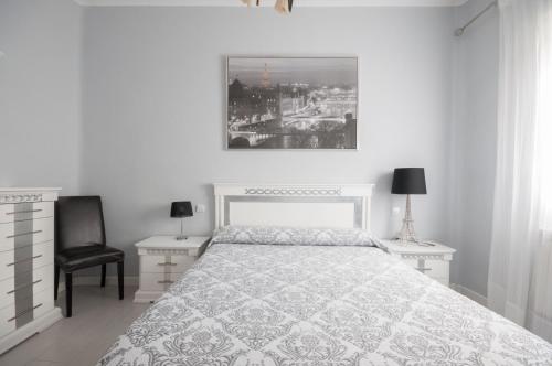 マドリードにあるApartamento 6 Mirasierrasの白いベッドルーム(ベッド1台、テーブル2台、椅子付)
