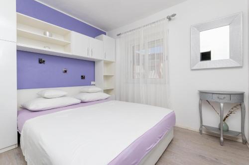 - une chambre blanche et violette avec un lit et une table dans l'établissement Apartments Babaja, à Trogir