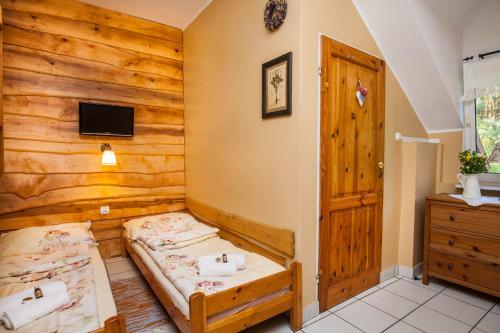a bedroom with two beds and a wooden wall at Pensjonat Iskra in Sztum