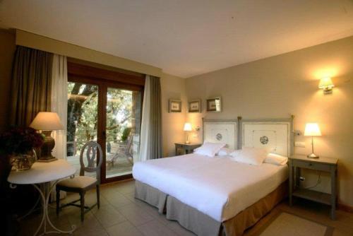 a bedroom with a large white bed and a window at Hotel Rural Las Rozuelas in Cercedilla