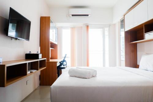 スラバヤにあるStrategic Studio Apartment at Orchard Mansion Supermall By Travelioのベッドルーム(白い大型ベッド1台、薄型テレビ付)