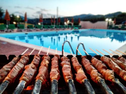 a row of sausages cooking on a grill near a swimming pool at Rifugio del Cavaliere in Ateleta