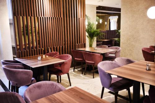 a restaurant with wooden tables and purple chairs at Hotel Ideja in Banja Luka