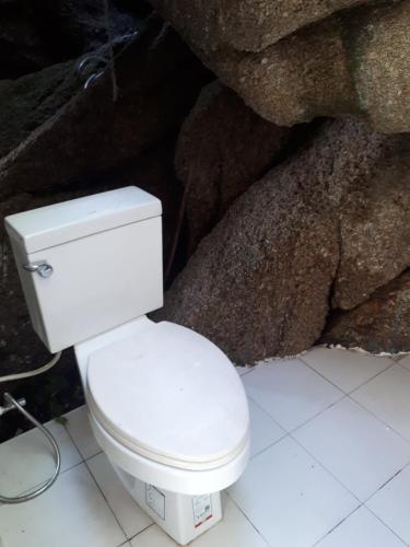 a white toilet in a bathroom next to rocks at Lighthouse Bungalows in Haad Rin