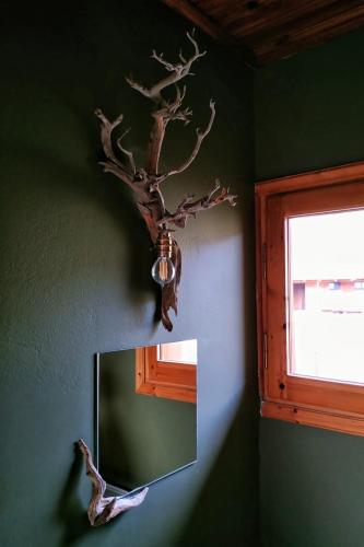 a mirror with a fake tree on the wall at Orias Guesthouse & Farm in Kalavrita