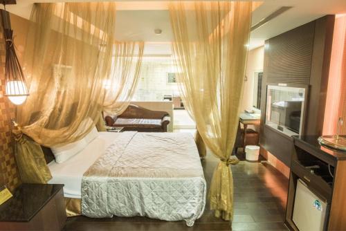 a bedroom with a bed with curtains and a television at 亞歷山大汽車旅館 in Kaohsiung
