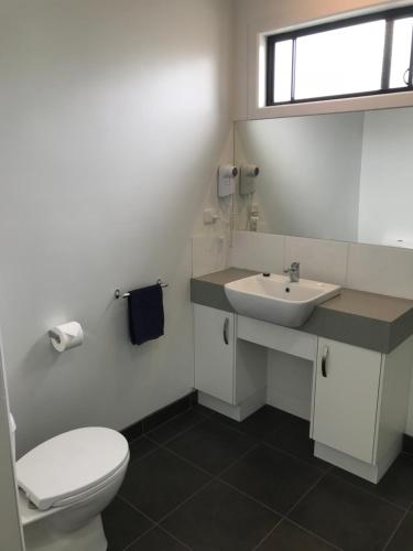 a bathroom with a white toilet and a sink at Prom Coast Holiday Lodge in Waratah Bay