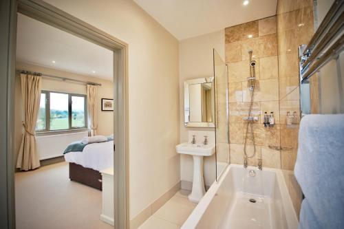La salle de bains est pourvue d'une douche, d'un lavabo et d'une baignoire. dans l'établissement Blacknest Golf and Country Club, à Alton
