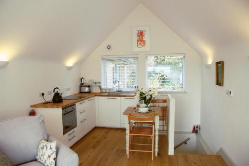 una cocina con armarios blancos y una mesa pequeña. en Marshlands Apartment en Lewes