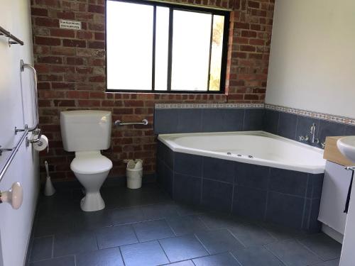 a bathroom with a tub and a toilet and a sink at Prom Coast Holiday Lodge in Waratah Bay