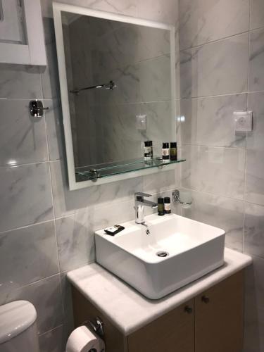 a bathroom with a white sink and a mirror at Akrogiali Rooms in Boukari