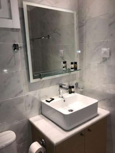 ブカリにあるAkrogiali Roomsのバスルーム(白い洗面台、鏡付)